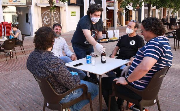 Unos amigos almuerzan en una terraza de Gandia. 