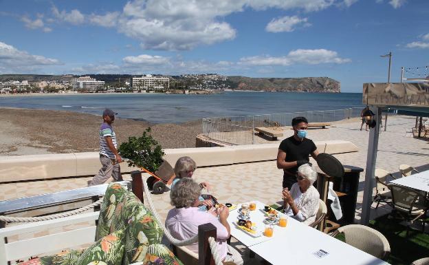 La Comunitat no pasa en su conjunto a la fase 1 de la desescalada, según comunicó el pasado viernes el Gobierno en una comparecencia ofrecida entre el ministro de Sanidad, Salvador Illa, y el director técnico, Fernando Simón. Sin embargo, algunos puntos como la comarca de la Marina comenzaban este lunes 11 de mayo el camino hacia la 'nueva normalidad'. En la imagen, unos extranjeros desayunan en la Punta del Arenal en Xàbia.