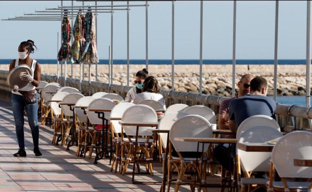 Una camarera atiende a los clientes en una terraza de Denia, alicante.