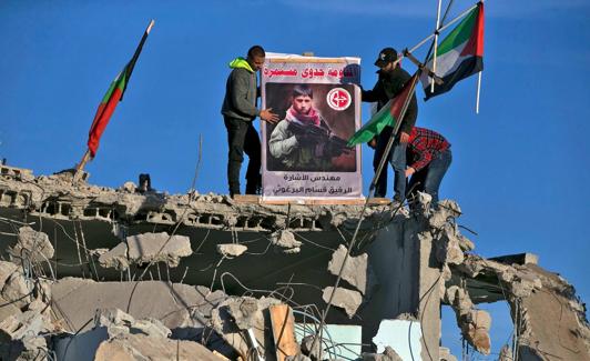 Dos palestinos colocan un cartel en las ruinas de un edificio.