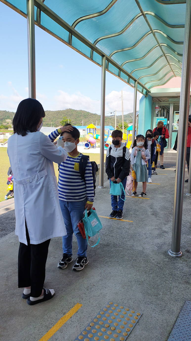 Corea del Sur, uno de los primeros países infectados por el coronavirus que surgió en la ciudad china de Wuhan, está recuperando poco a poco la normalidad. Muestra de ello ha sido el regreso a las clases de sus estudiantes. Los primeros en volver a los pupitres han sido los alumnos de bachillerato; el resto se irá incorporando poco a poco. No obstante, el inicio del curso escolar se ha hecho con una serie de medidas para evitar los contagios entre los estudiantes: el uso de mascarillas en todo momento, limpieza de los pupitres, ventilación continua de los cuartos, mámparas en el comedor y en las mesas y tomas de temperatura al entrar al colegio, todo ello, manteniendo las distancias de seguridad. 