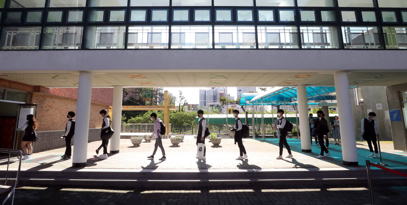 Corea del Sur, uno de los primeros países infectados por el coronavirus que surgió en la ciudad china de Wuhan, está recuperando poco a poco la normalidad. Muestra de ello ha sido el regreso a las clases de sus estudiantes. Los primeros en volver a los pupitres han sido los alumnos de bachillerato; el resto se irá incorporando poco a poco. No obstante, el inicio del curso escolar se ha hecho con una serie de medidas para evitar los contagios entre los estudiantes: el uso de mascarillas en todo momento, limpieza de los pupitres, ventilación continua de los cuartos, mámparas en el comedor y en las mesas y tomas de temperatura al entrar al colegio, todo ello, manteniendo las distancias de seguridad. 