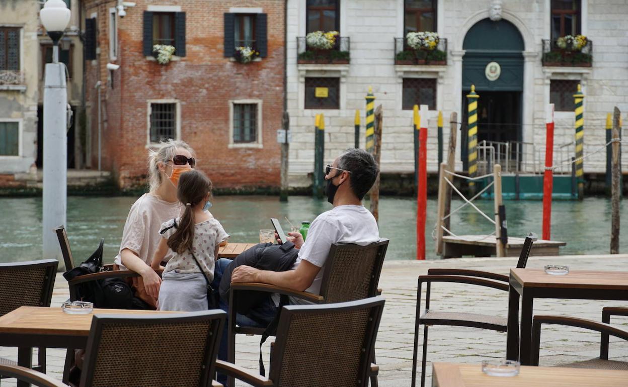 Una familia toma un refresco en una terraza en Venecia.