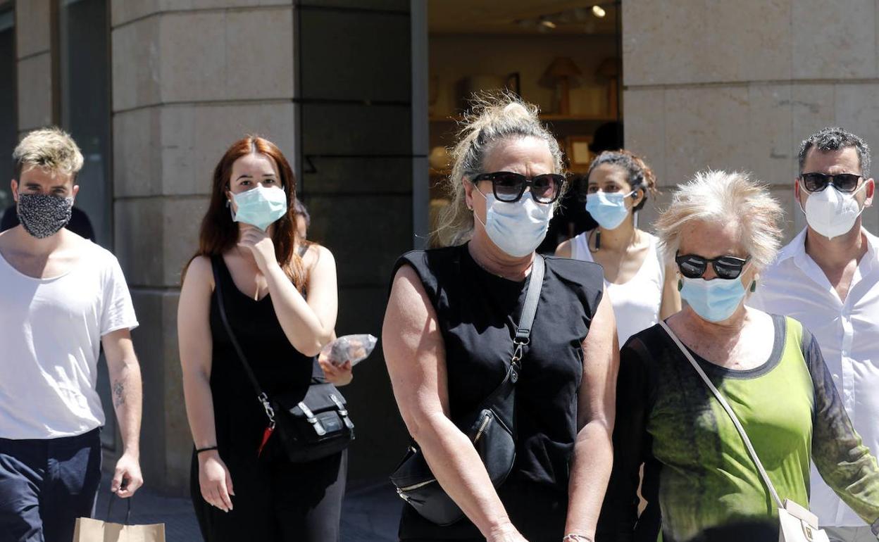 Varias personas pasean por el centro de Valencia llevando mascarilla.