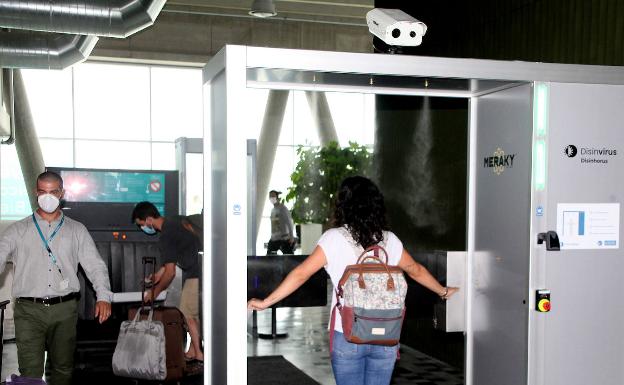 Una de las pasajeras es rociada con agua ozonizada antes de entrar en el ferry.