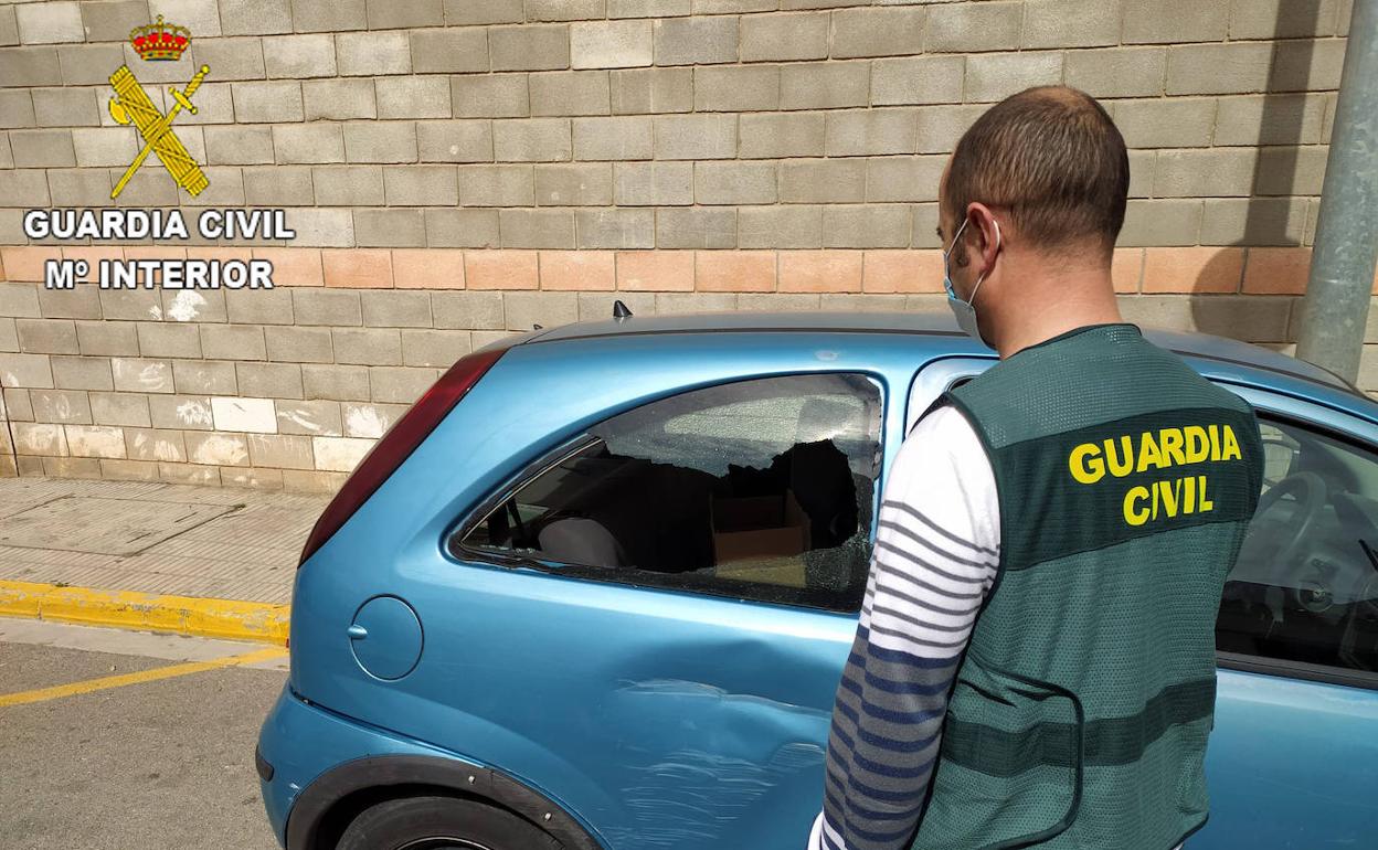 Un agente ante un coche que ha sufrido un robo. 