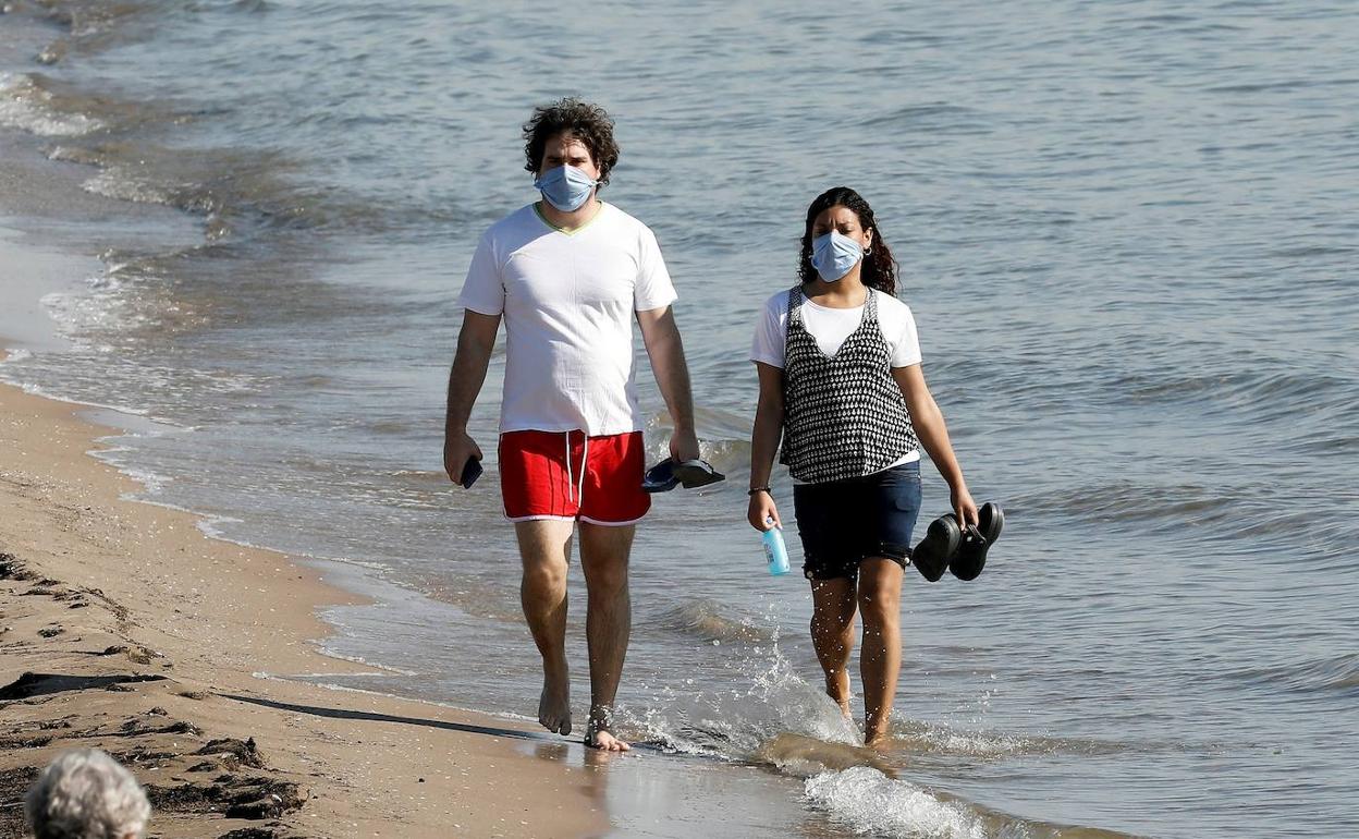 Una pareja camina por una playa de Valencia.