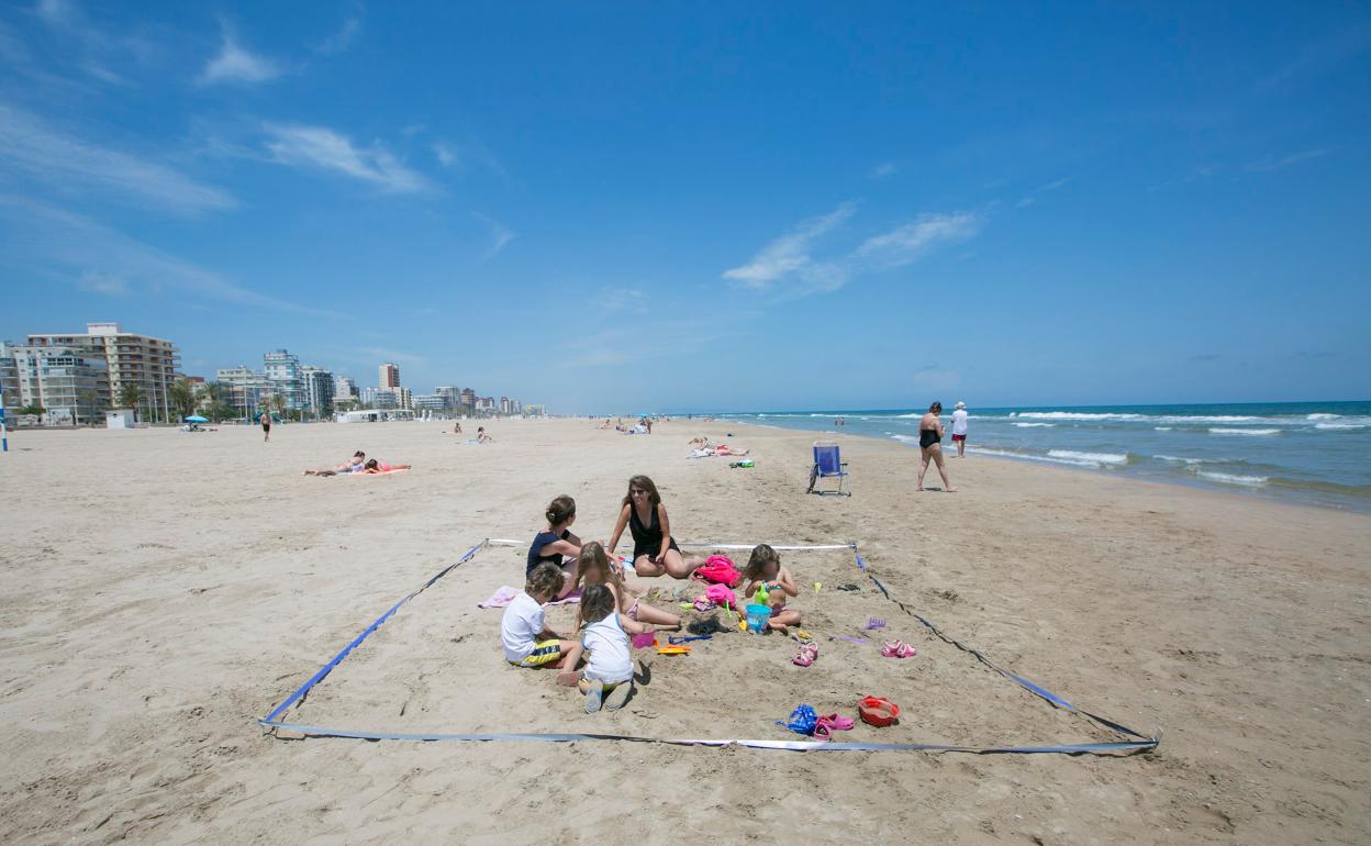 Una familia en un espacio parcelado de la playa de Gandia. 