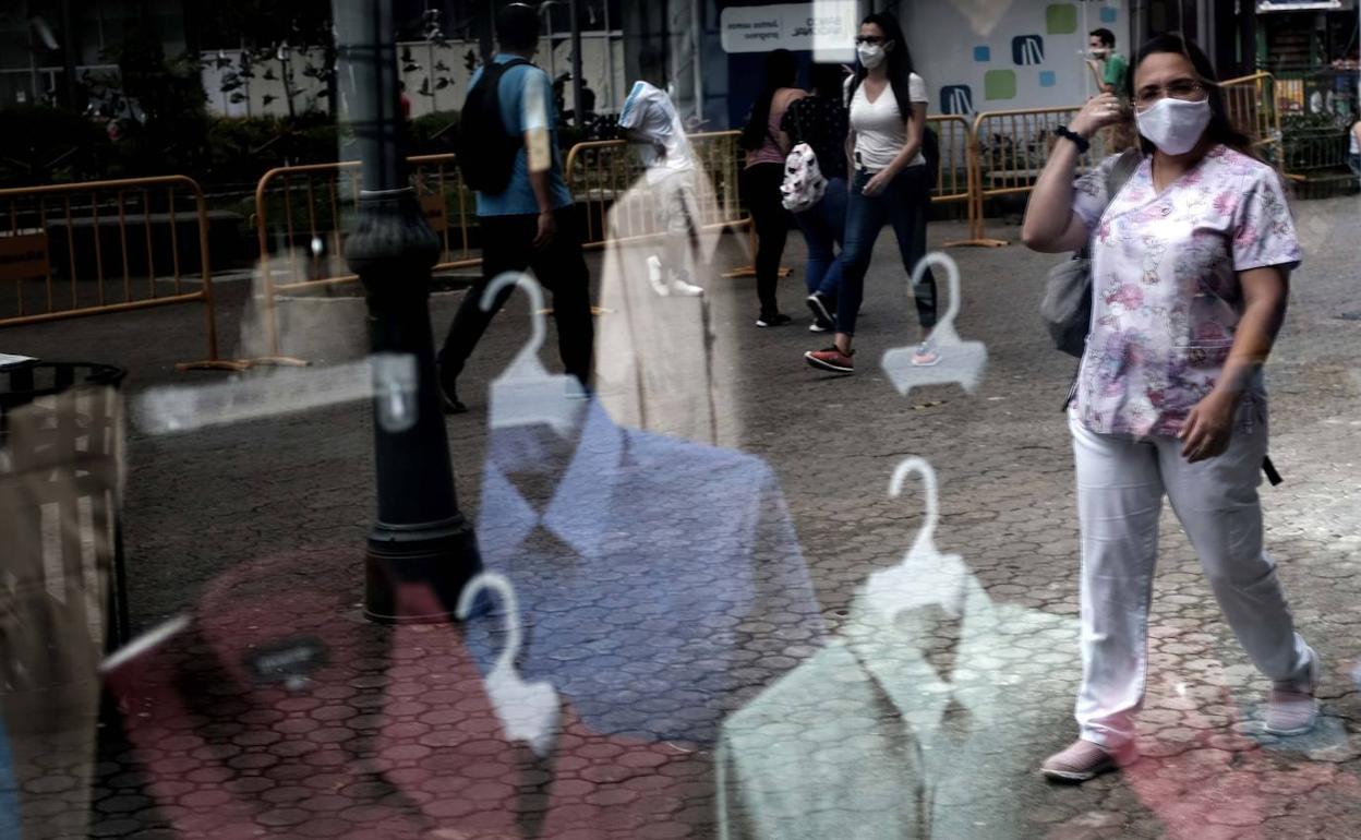 Una mujer camina delante de una tienda de ropa. 