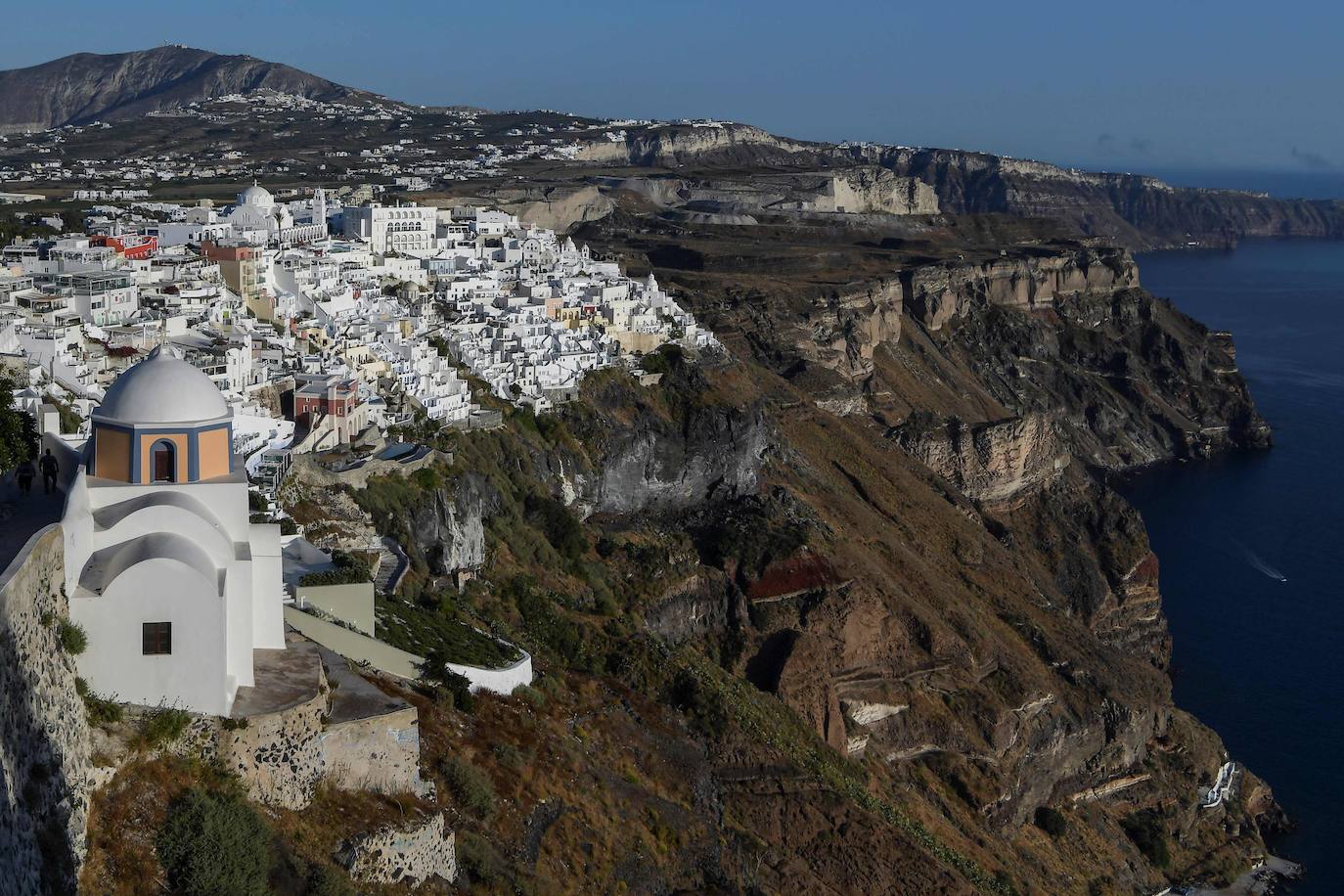 En las tranquilas callejuelas de Fira, la ciudad principal de la isla, el tiempo avanza al ritmo de la campana de la iglesia Aghia Eleftherios -en la imagen-. Como un recordatorio de las horas que la separan ahora de la irrupción de turistas. "Les esperamos desesperadamente. Los necesitamos. Si no vienen, ¿cómo vamos a sobrevivir?", declara Michalis Drosos, que trabaja en una tienda de recuerdos del centro de Fira.