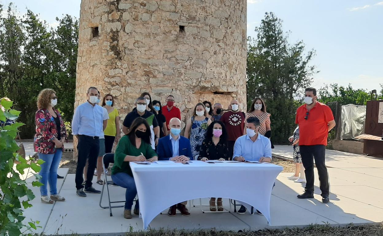 Los representantes de Compromís y PSPV firman el pacto, en la Torre de Guaita, ante militantes de los dos partidos.