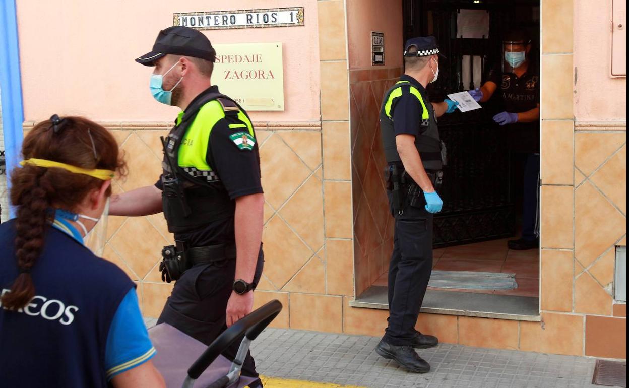 Un policía local entrega una carta certificada urgente al dueño de la pensión Zagora en Algeciras (Cádiz), que fue aislada con 17 personas dentro por un brote de coronavirus. 