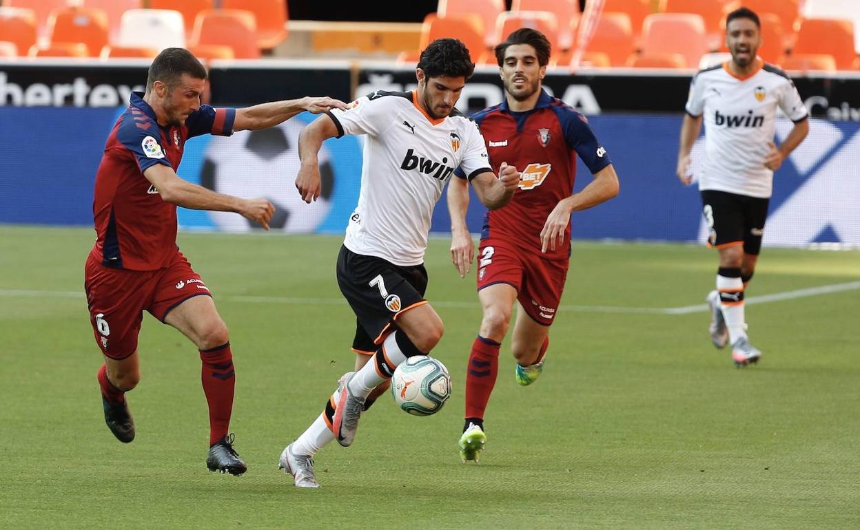 Guedes, con la primera equipación del Valencia, escapa de Oier y el exblanquinegro Nacho Vidal. 