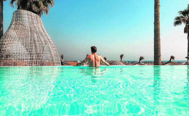 Un joven disfruta de las vistas en la piscina infinita de un resort de la Comunitat Valenciana. 