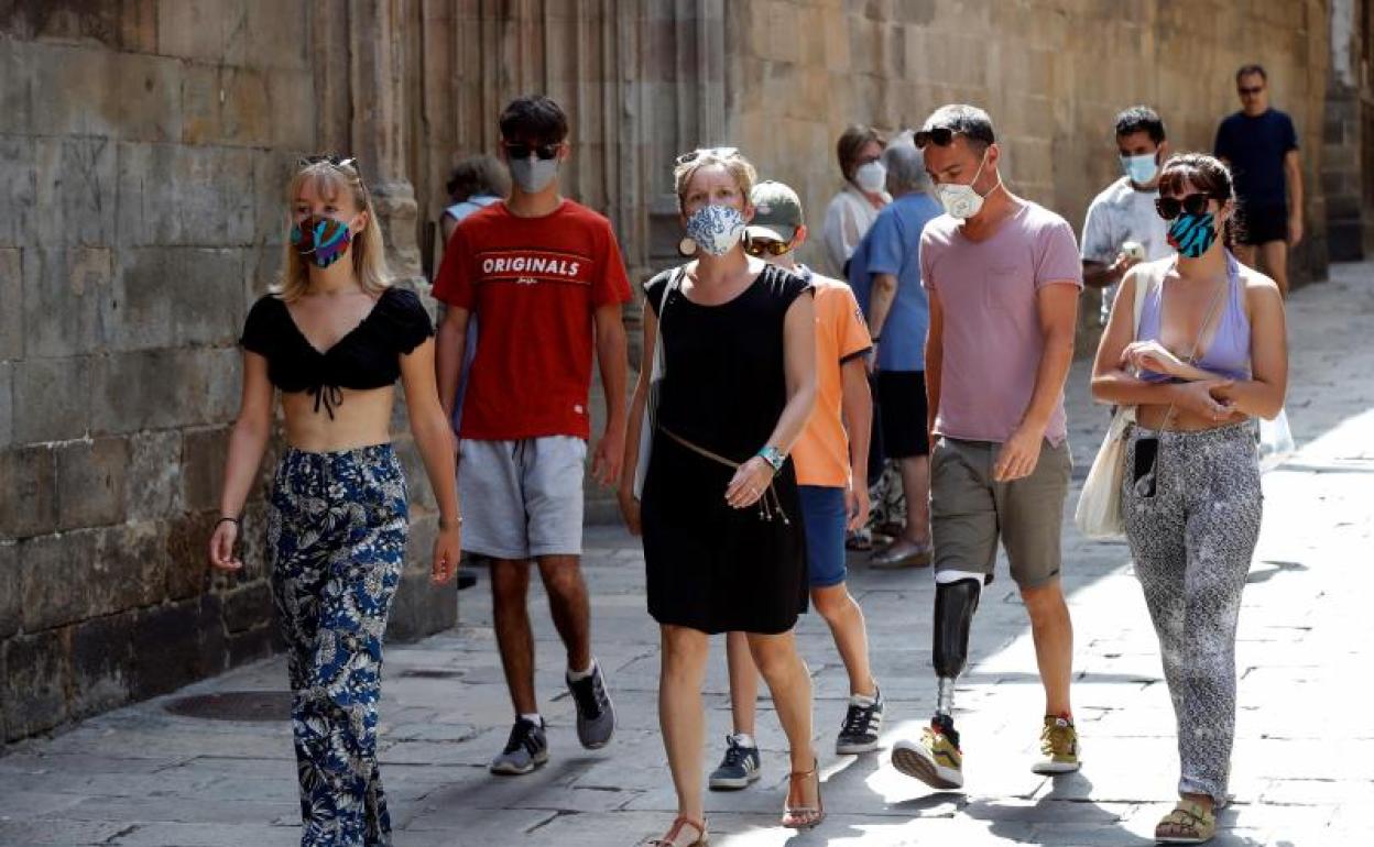 Un grupo de personas pasea por el barrio gótico de Barcelona protegidos con sus mascarilla