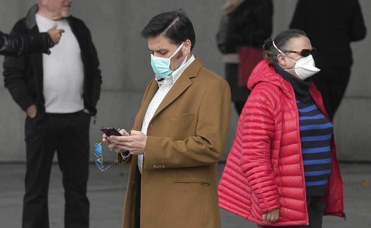 Un hombre pasea con una mascarilla quirúrgica, junto a una mujer que porta una de tipo higiénico. 