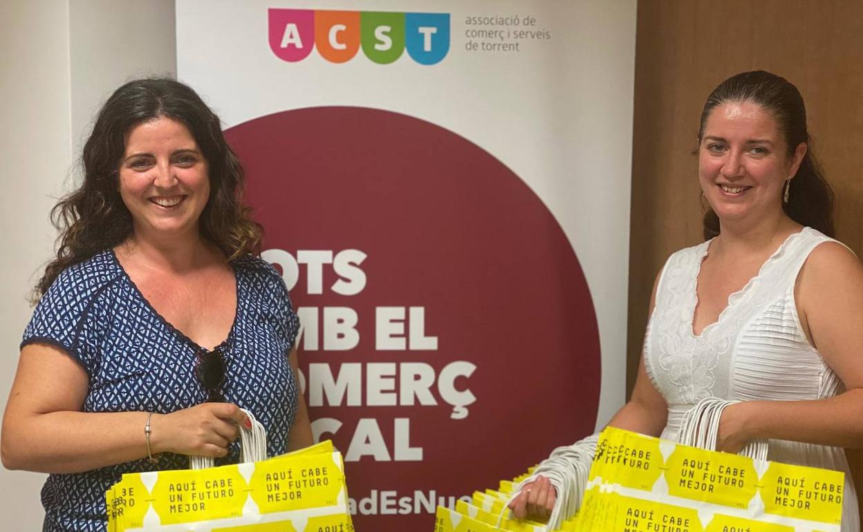 Dos comerciantes con las bolsas que se regalarán. 