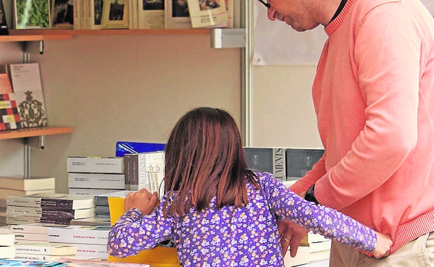 Una niña curiosea el expositor de una librería. 