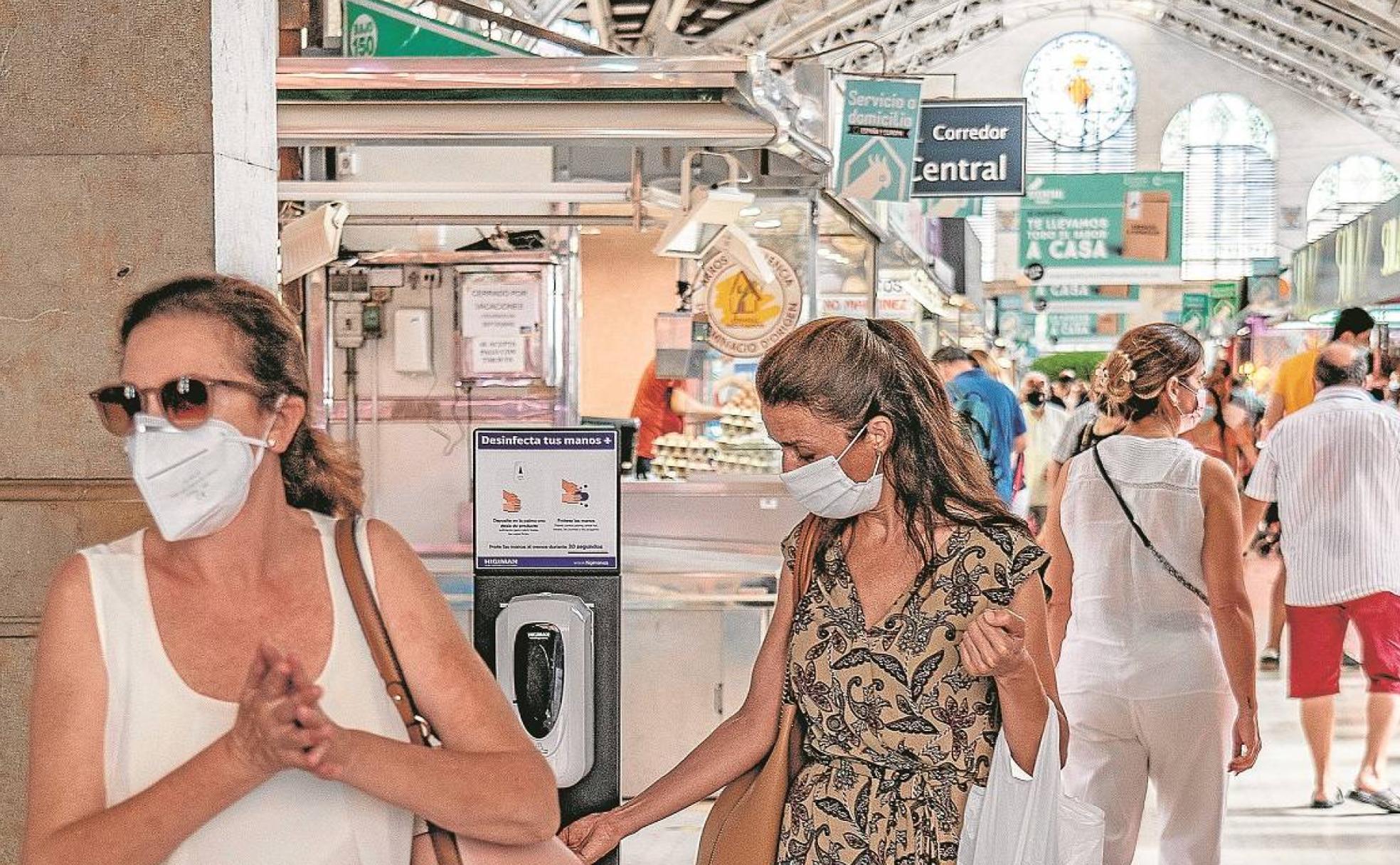 Una clienta del Mercado Central de Valencia recuerriendo a un dispensador de gel. 