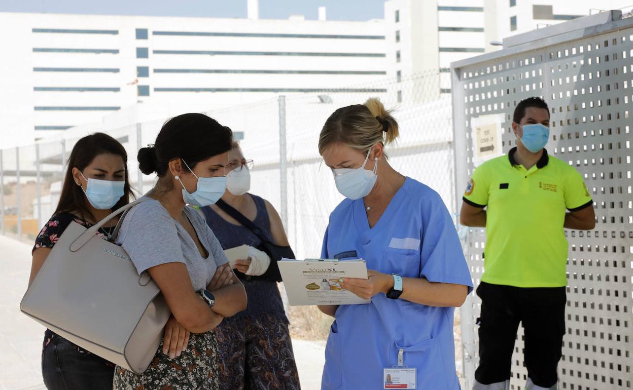 Varias personas conversan con el personal sanitario del hospital para poder acceder al centro. 