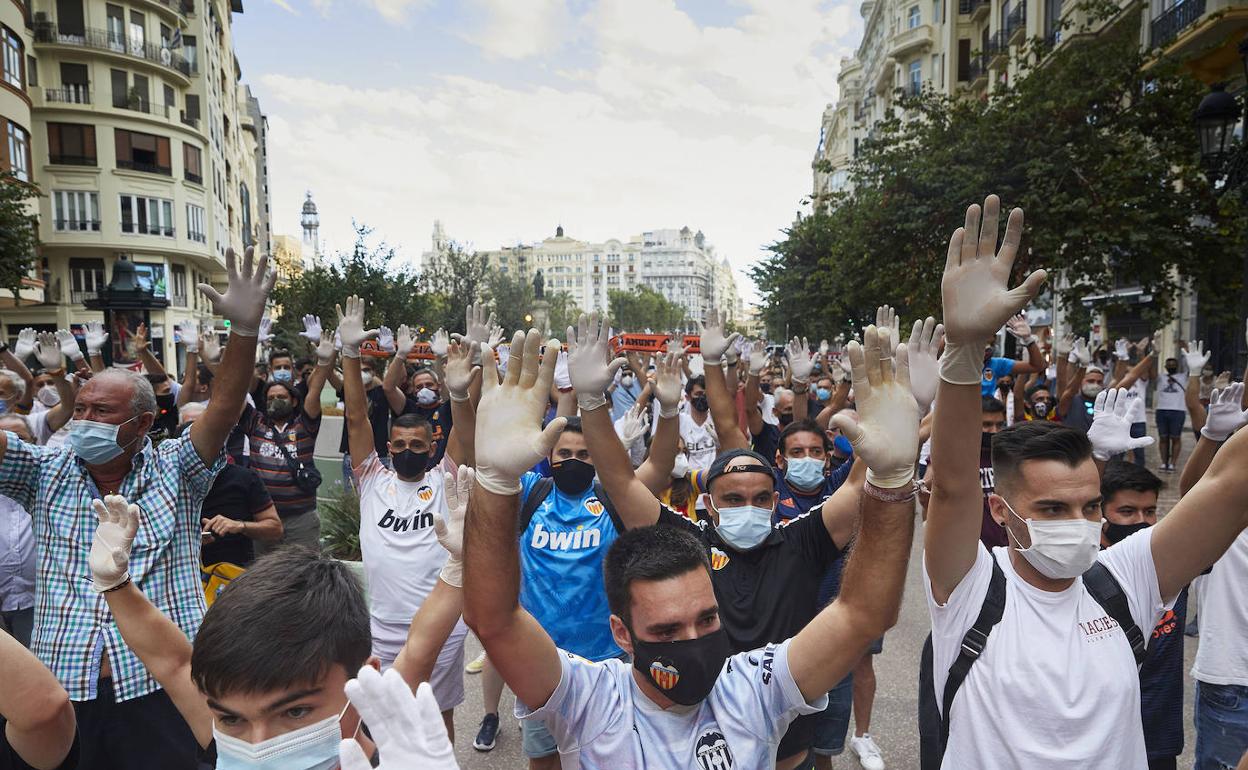 Los aficionados levantan sus manos con guantes blancos en señal de protesta contra Meriton. 