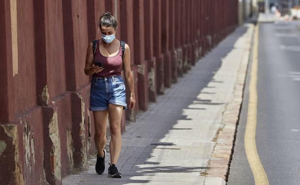 Una mujer paseo por Valencia con mascarilla. 