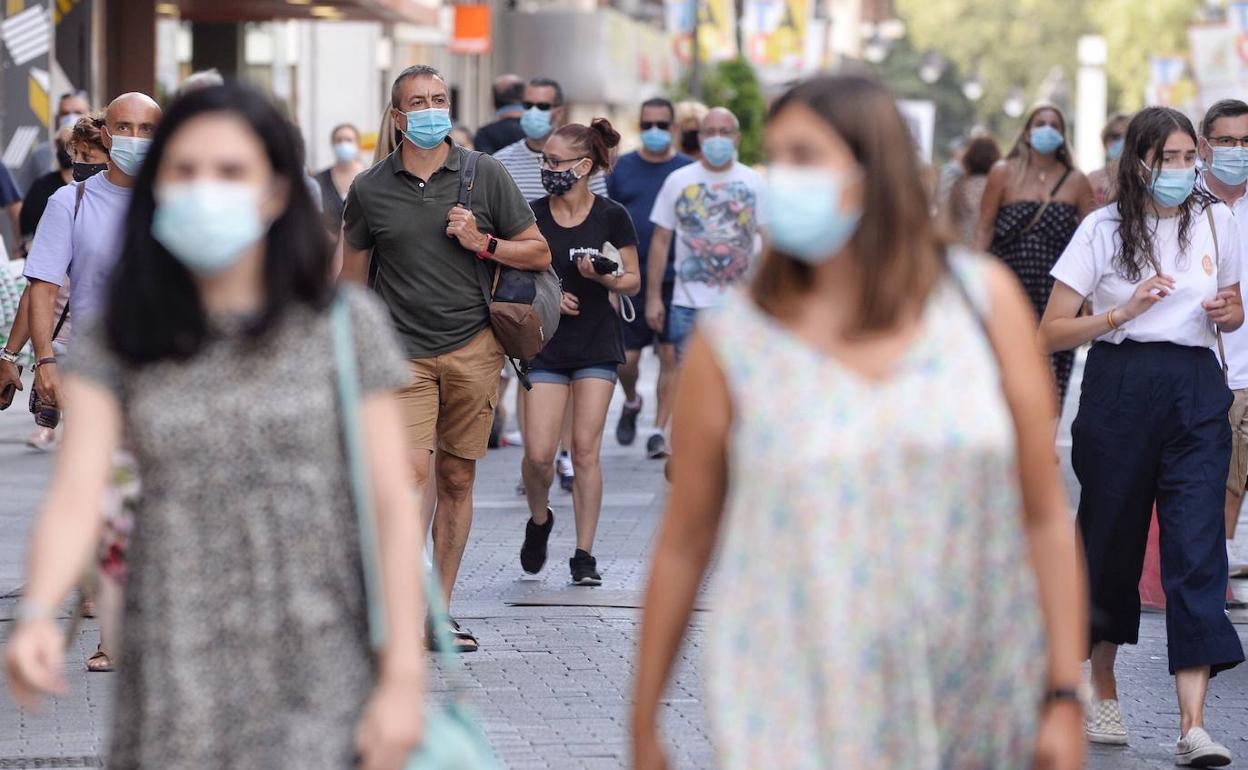 Paseantes en la calle con la mascarilla puesta.