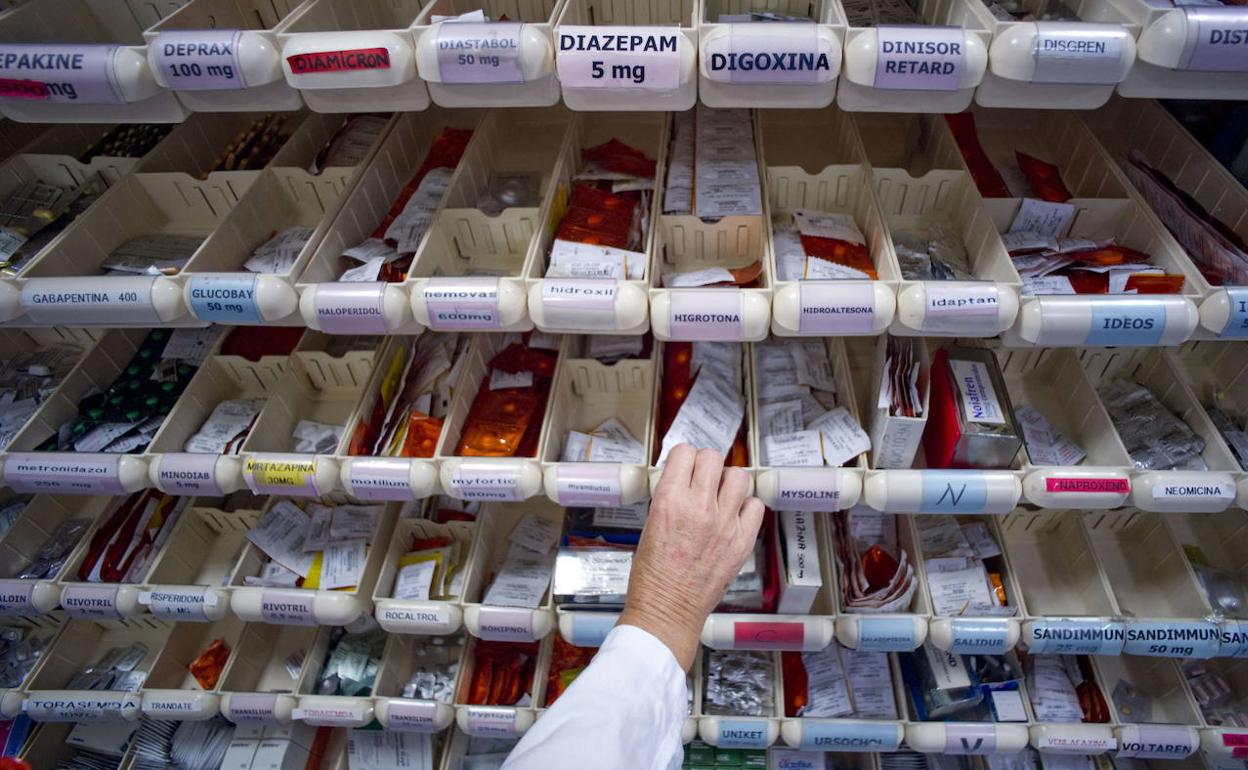 Una farmacéutica toma un mediacamento de un estante. 