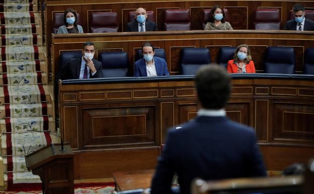 Pablo Casado, de espaldas, interviene en la sesión de control al Gobierno, mientras que Pedro Sánchez le escucha en su escaño.