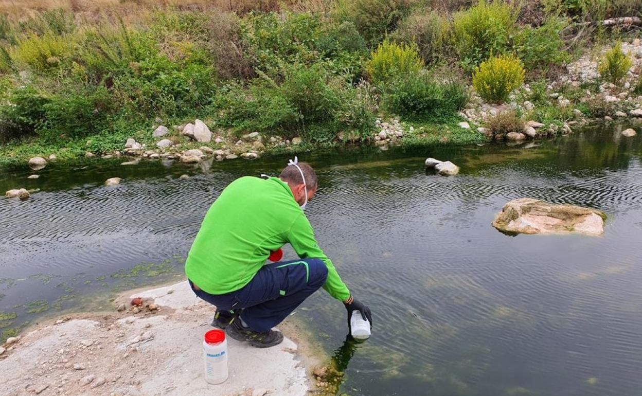 Un operario recoge muestras de agua del río. 