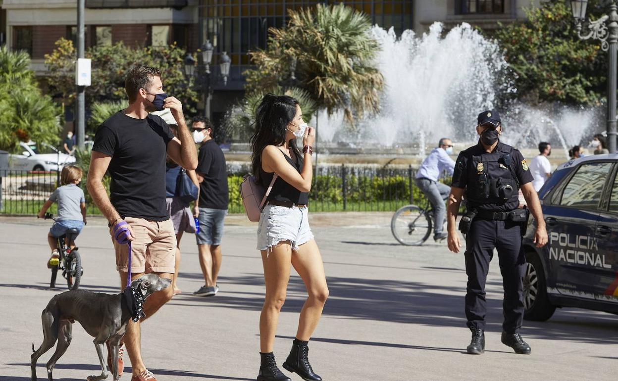 Personas paseando por Valencia junto a un agente de la Policía Nacional. 