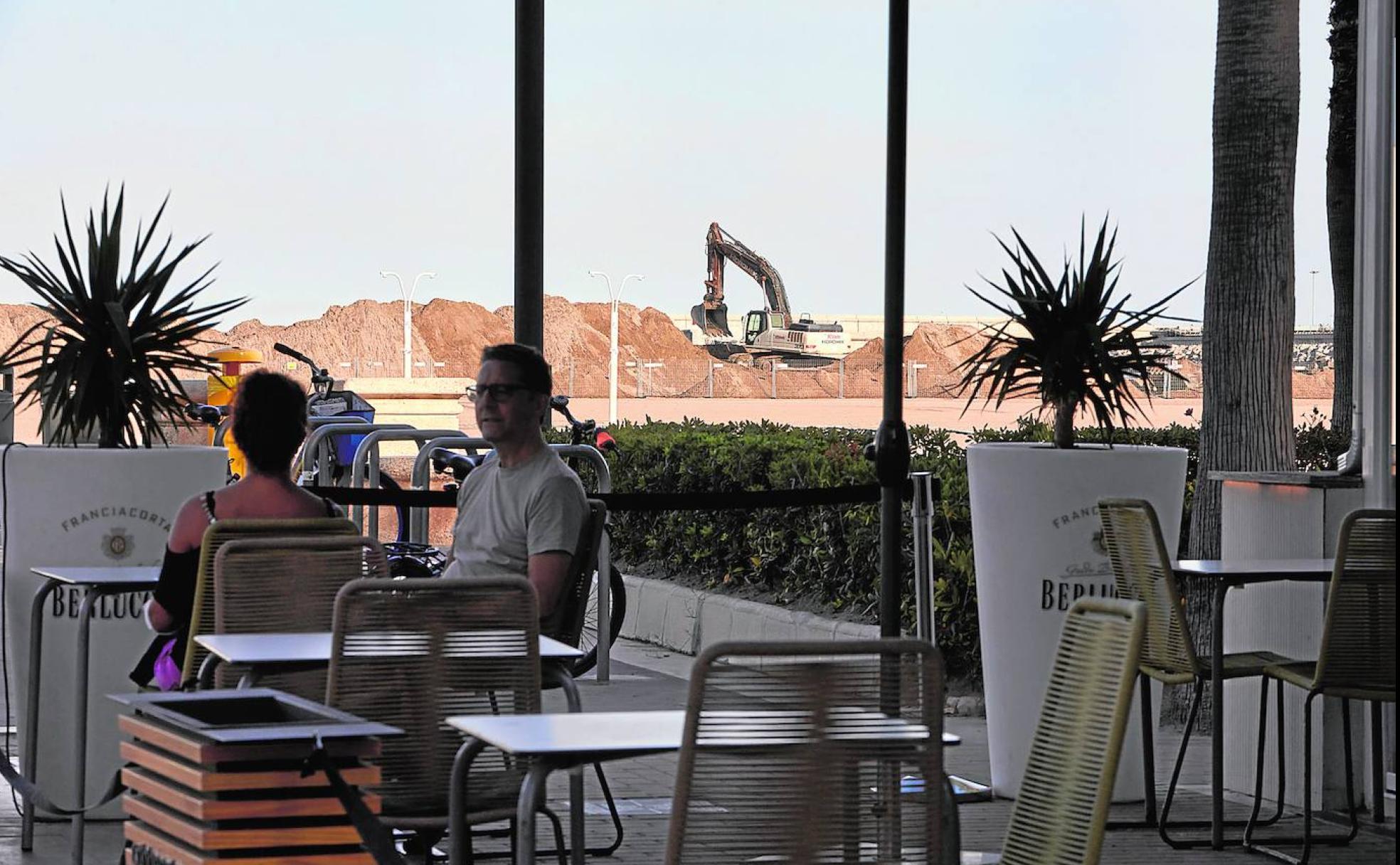 Las Arenas. Máquinas cargan arena en la playa delante de uno de los restaurantes de la zona. 