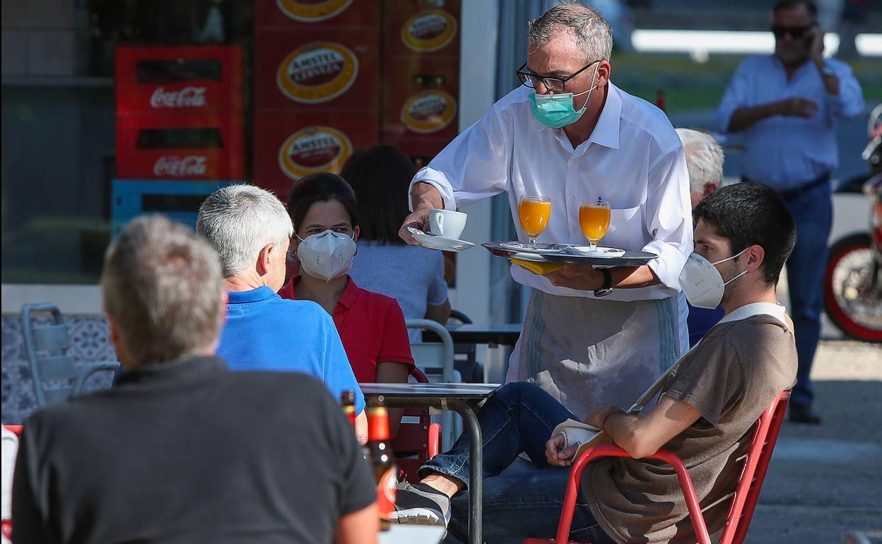 Un camarero sirve a los clientes en una terraza de un bar en Valencia.