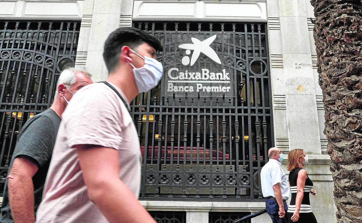 Varias personas pasan por delante de la sede social de CaixaBank en el antiguo Banco de Valencia. 