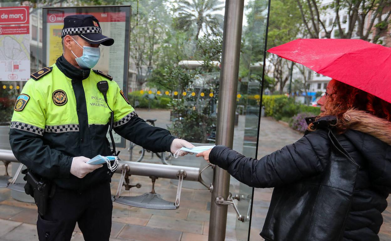 Un agente de la Policía Local entrega mascarillas a una viandante. 