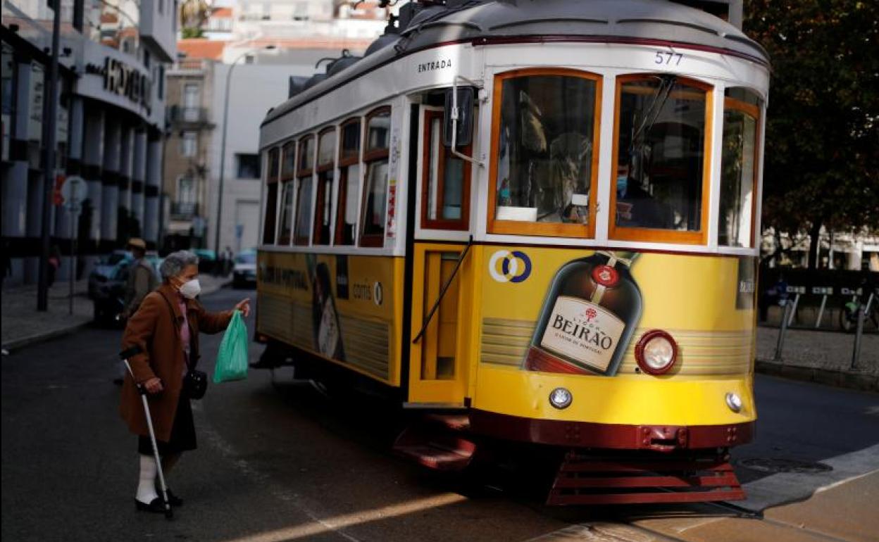 Una mujer con mascarilla se acerca a un tranvía en Lisboa, Portugal.