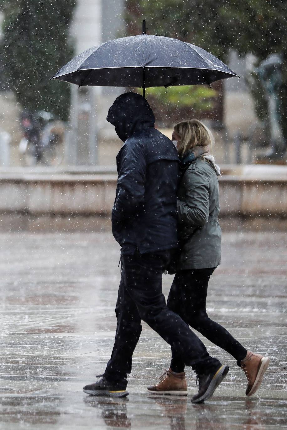 Dos personas se protegen de la lluvia con paraguas y chubasqueros en una céntrica calle de Valencia, este miércoles.