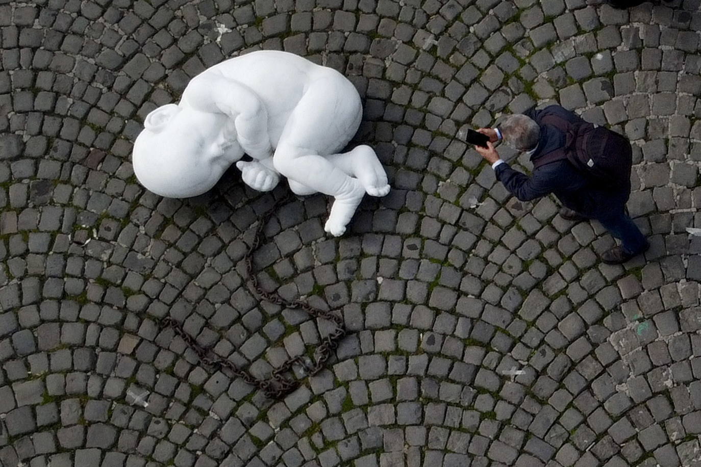 Una escultura en mármol blanco, que representa a un niño acurrucado y con una muñeca encadenada, ha sido abandonada en el centro de la plaza Plebiscito, en Nápoles. 