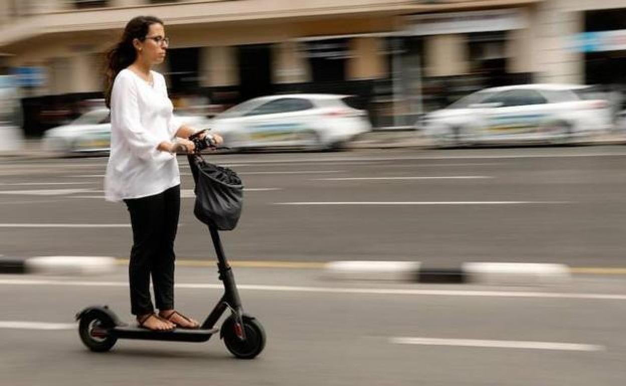 Una usuaria de patinete circula por la vía pública con uno de estos vehículos.