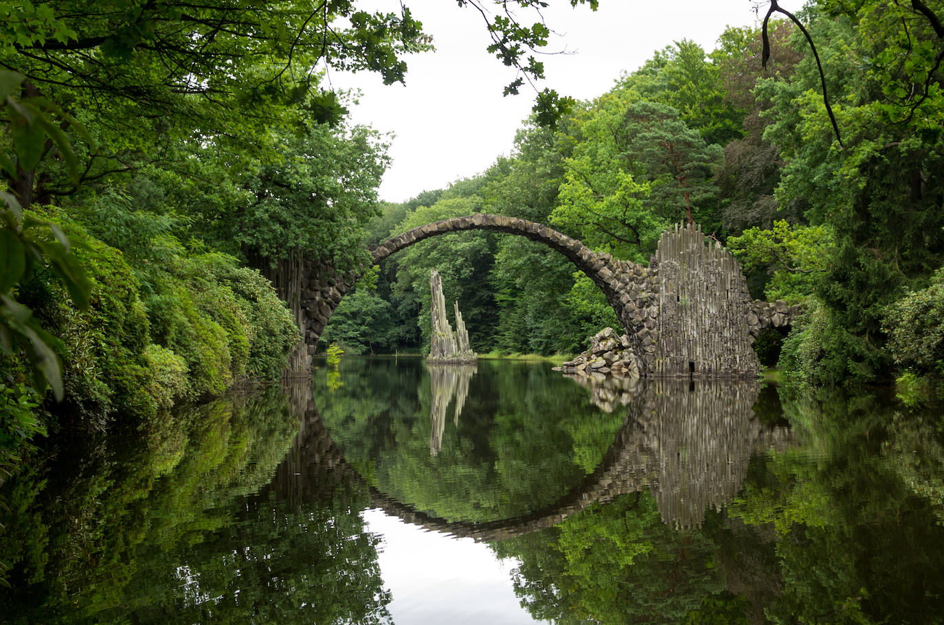 1.- Parque Kromlauer (Alemania) | El puente Rakotzbürke, conocido como el puente del diablo -en la imagen- se encuentra en medio del parque Kromlauer. Está en el municipio de Gablenz, a tan solo seis kilómetros de la frontera de Alemania con Polonia. Tiene una forma de semicírculo perfecta y su reflejo en el agua provoca que se vea una circunferencia completa.