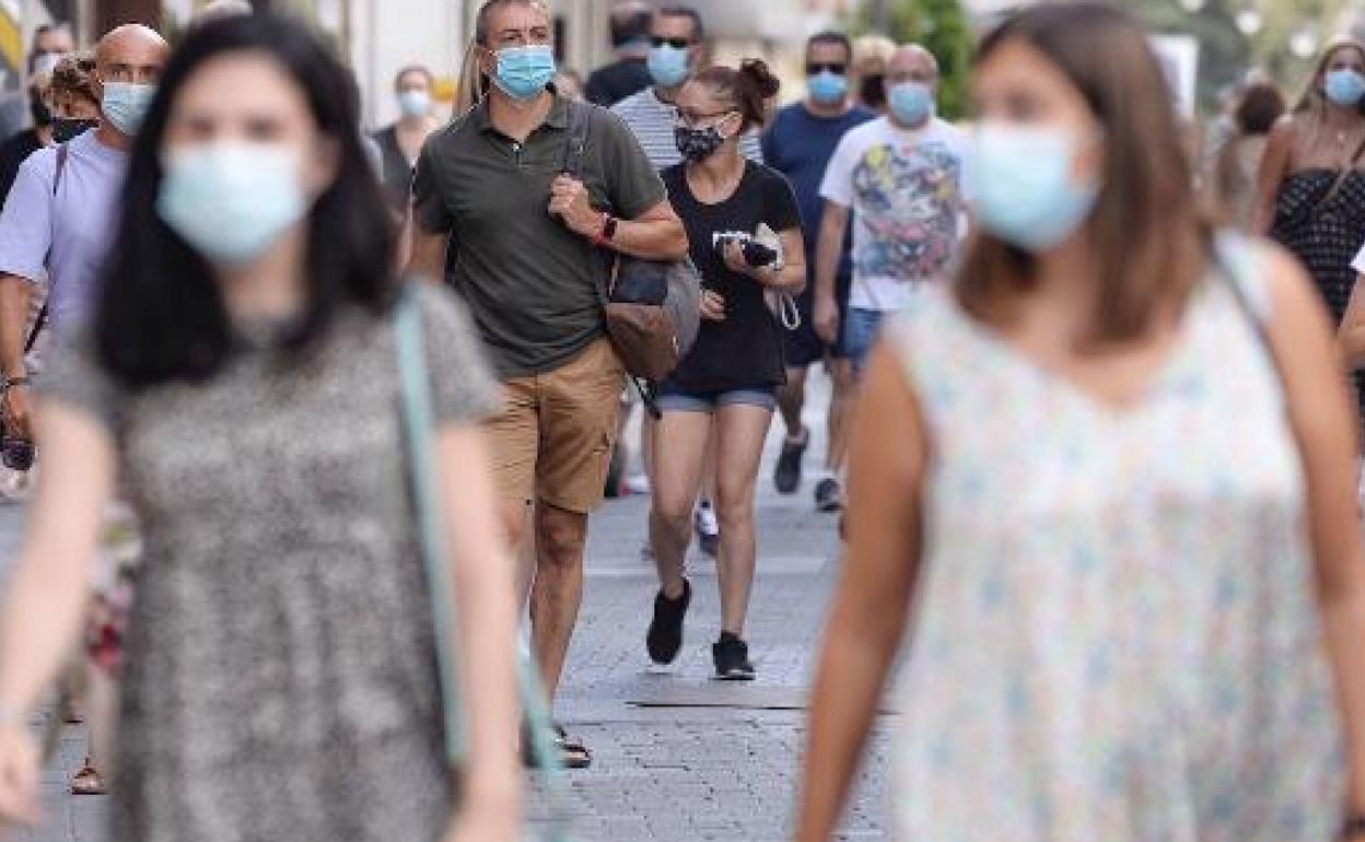 Varias personas andando en Valencia con mascarilla. 