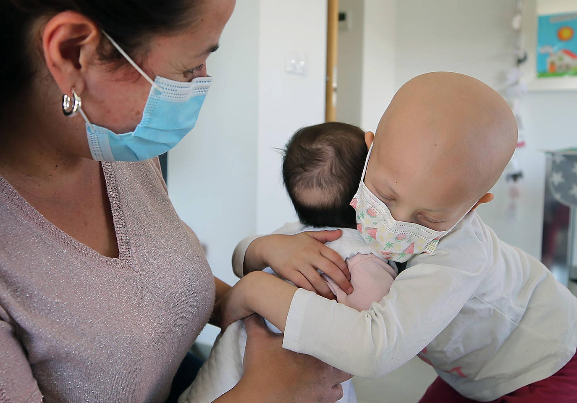 Lucía abraza con delicadeza a Silvia, su hermana pequeña, observadas por Adriana, la madre.