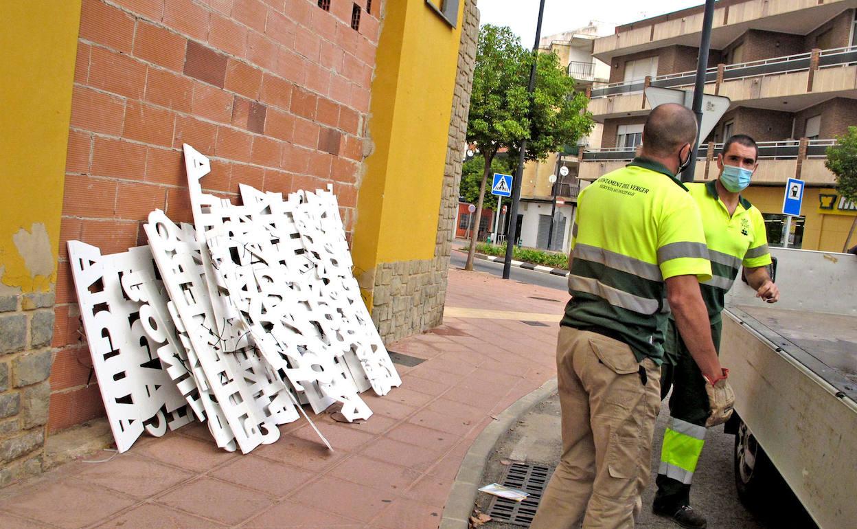 Los operarios dejan en una pared los carteles recuperados tras ser esparcidos por la vía pública.