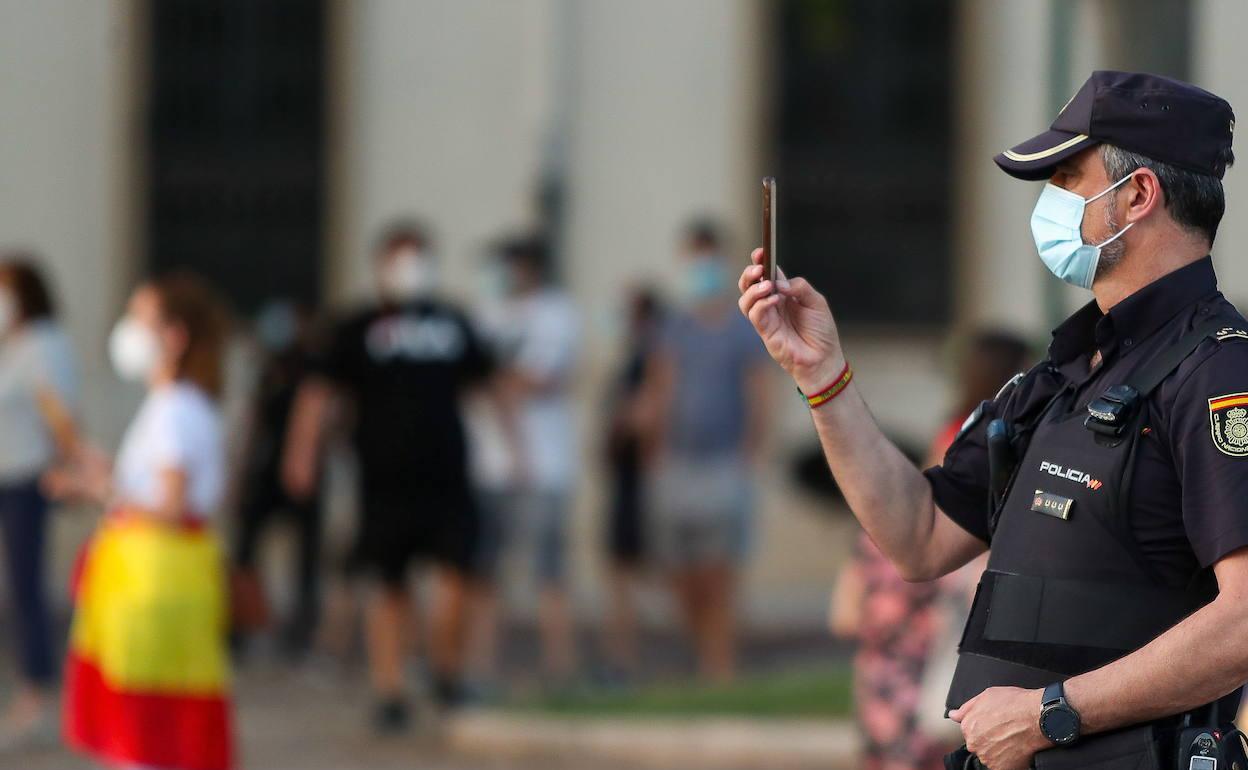 Un agente de la Policía Nacional sostiene un teléfono móvil en Valencia, en una imagen de archivo. 