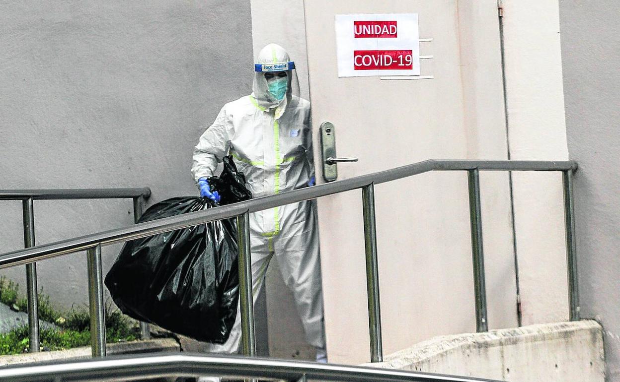 Sanitario saca la basura al salir de una unidad donde se trata a pacientes infectados de Covid en un hospital