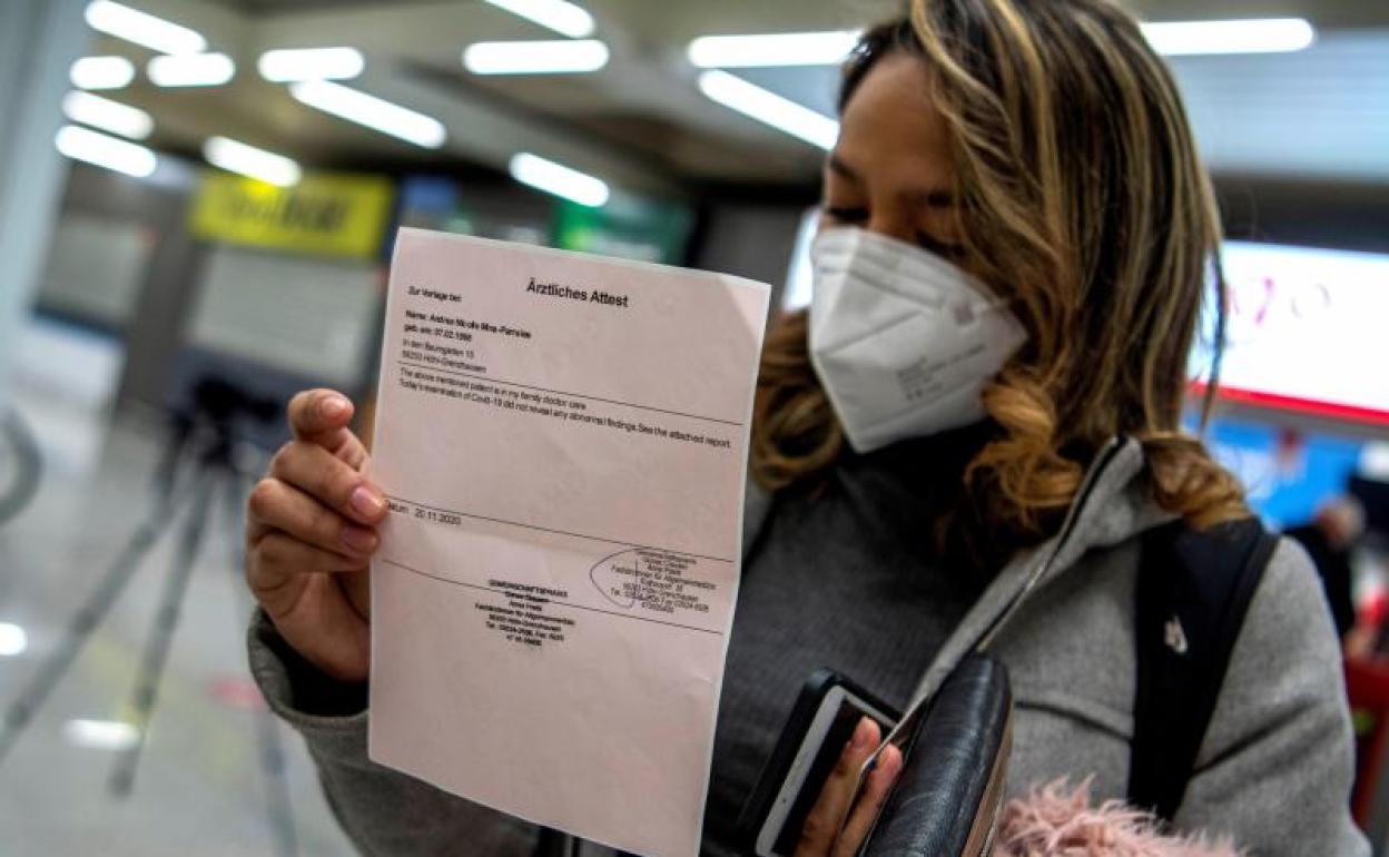 Una pasajera procedente de un vuelo de Colonia (Alemania) muestra el resultado negativo de su PCR tras aterrizar en el Aeropuerto de Palma de Mallorca.