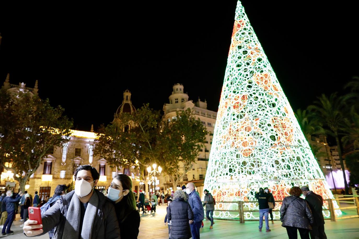 El alcalde Ribó ha asistido esta tarde al encendido en la plaza del Ayuntamiento, acompañado por las falleras mayores de Valencia, Consuelo Llobell y Carla García. La iluminación se estrena en la ciudad con quejas por el escaso gasto frente al aumento en otras ciudades para ayudar al comercio.