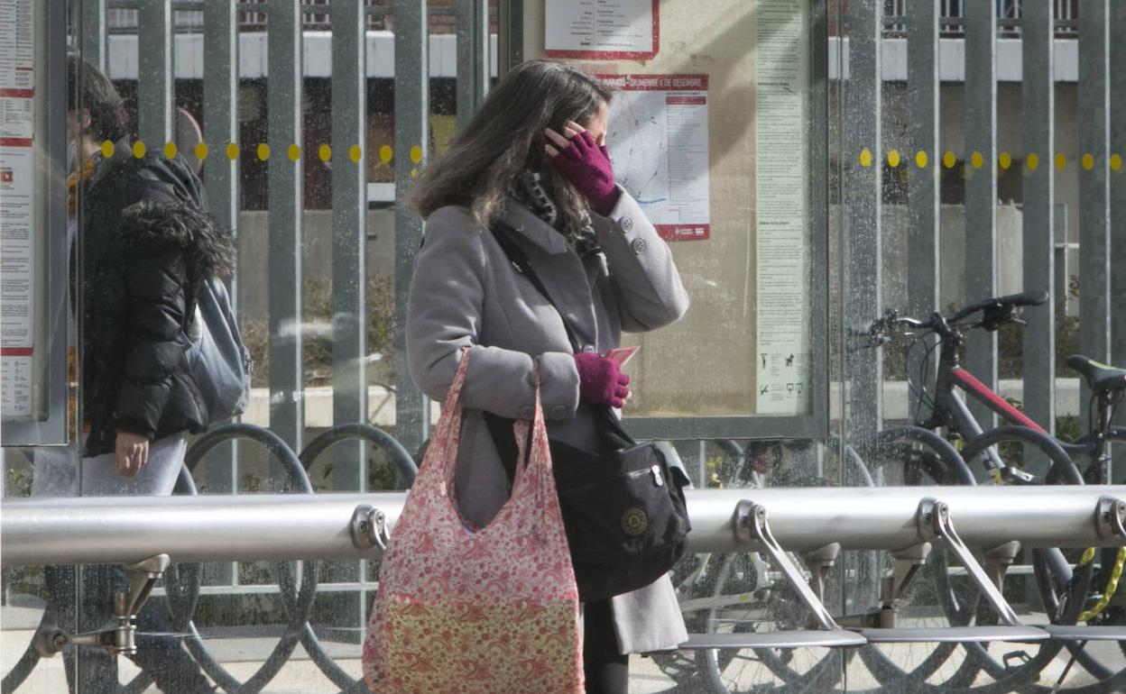 Una mujer se protege del viento en Valencia