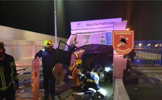 Los bomberos trabajan en el rescate del conductor que ha chocado contra la caseta en el Puerto de Alicante. 