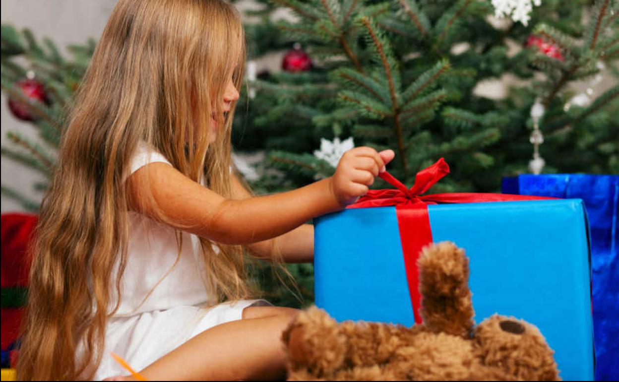 Niña abriendo un regalo de Navidad.